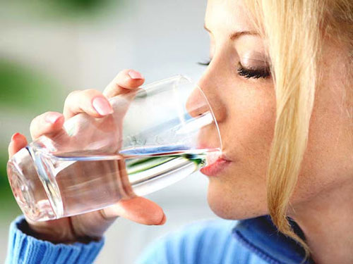 Closeup of adult blond woman drinking water.